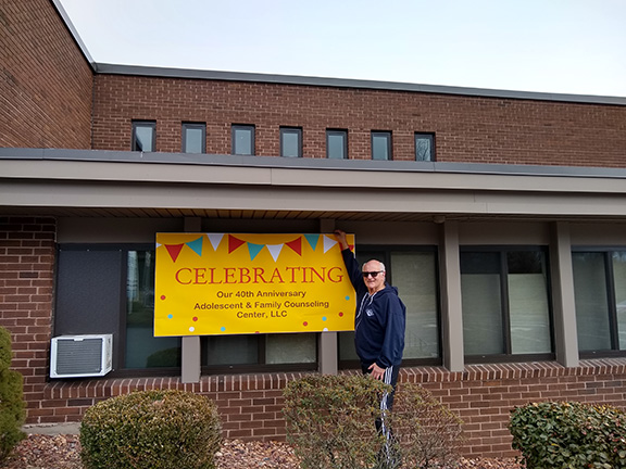 Herb Rosenfield in front of office banner
